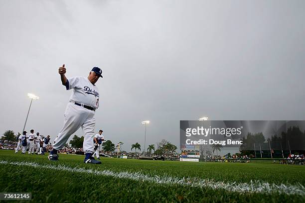 Tommy Lasorda of the Los Angeles Dodgers gives fans a thumbs up as he leaves the field when the rain canceled the game against the Boston Red Sox...