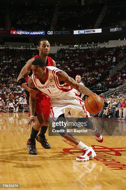 Tracy McGrady of the Houston Rockets drives around Morris Peterson of the Toronto Raptors at the Toyota Center on February 28, 2007 in Houston,...