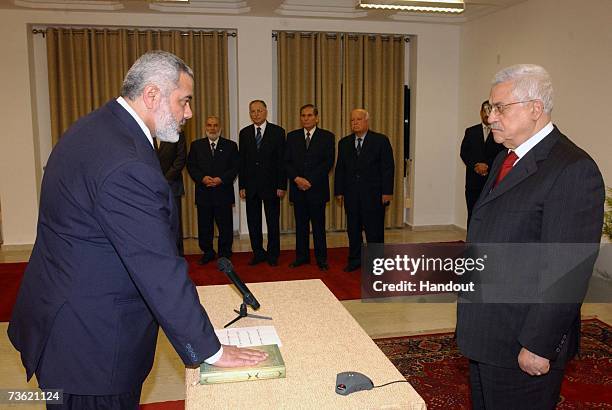 In this photo provided by the Palestinian Press Office, Palestinian Authority Prime Minister Ismail Haniyeh of Hamas, places his hand on the Quran,...