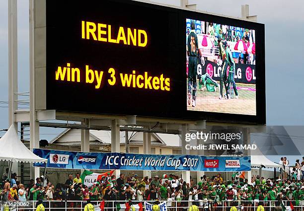 The electronic scoreboard shows the result as Irish cricket fans celebrate their team's victory over Pakistan at the end of the Group D match of the...