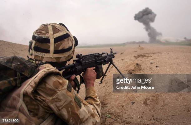 British commando Lee Oliver fires at Taliban only 400 meters away as a plume of smoke rises from an airstrike during a sunrise attack on Taliban...