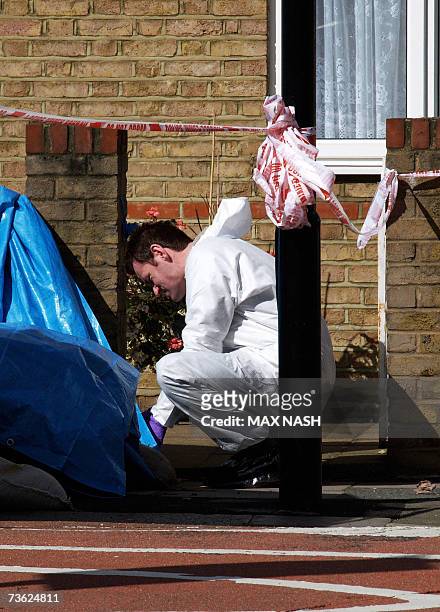 London, UNITED KINGDOM: A British forensic expert searches under a murder scene 18 March 2007, after a 15-year old schoolboy was stabbed to death 17...
