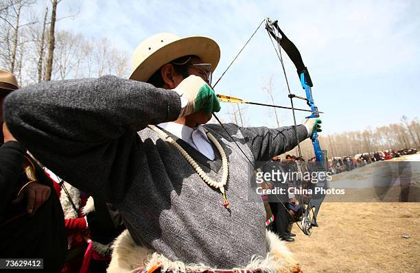 Tibetan contestant aims a bow and arrow during the Hualong County Ethnic Archery Contest on March 17, 2007 in Hualong County of Qinghai Province,...