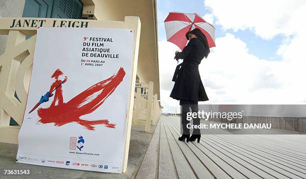 Woman walks past a poster announcing the 9th Asian Film Festival 19 March 2007 in Deauville, northwestern France. The festival will present a large...