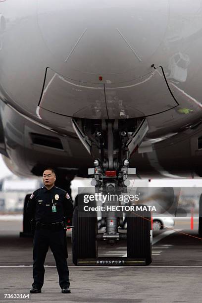 Los Angeles, UNITED STATES: An Los Angeles Police Department officer stands near The Airbus A380 turbo engine as it parks along the runway at the Los...