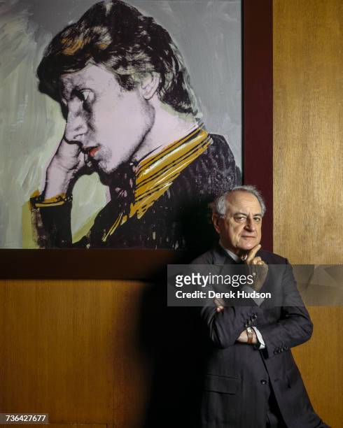 French industrialist and patron Pierre Bergé in his office at the Yves Saint Laurent headquarters with a portrait of Saint-Laurent by Andy Warhol....