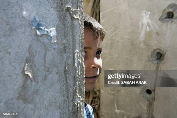 An Iraqi homeless boy peers from a bullet riddled wall at the abandoned Saddam's Republican Guard Air Force headquarters in Baghdad, 18 March 2007....