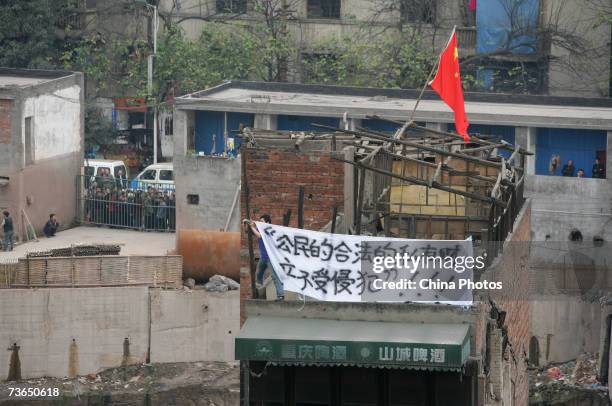 The house owner who refused to accept a compensation deal by a property developer, hangs a banner reading "citizens's private properties should not...