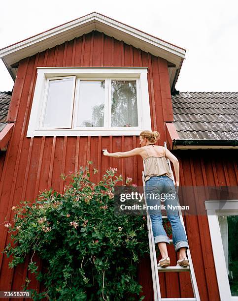 a woman painting a house. - painting house exterior stock pictures, royalty-free photos & images