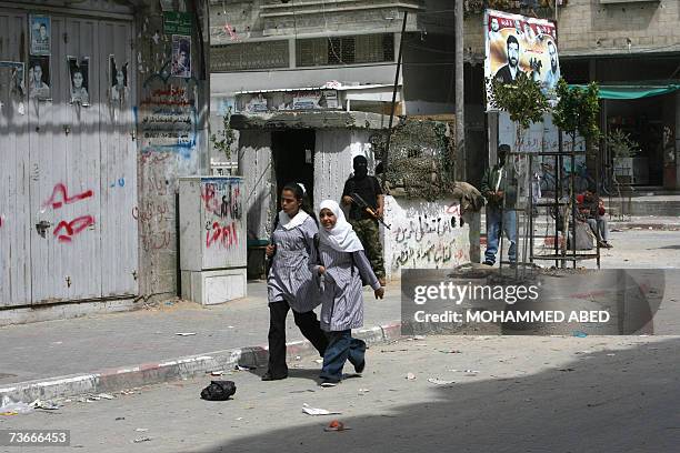 School girls walks past armed Palestinian militants from the al-Aqsa Martyr's Brigades as they stand on the streets of Beit Lahiya in the northern...