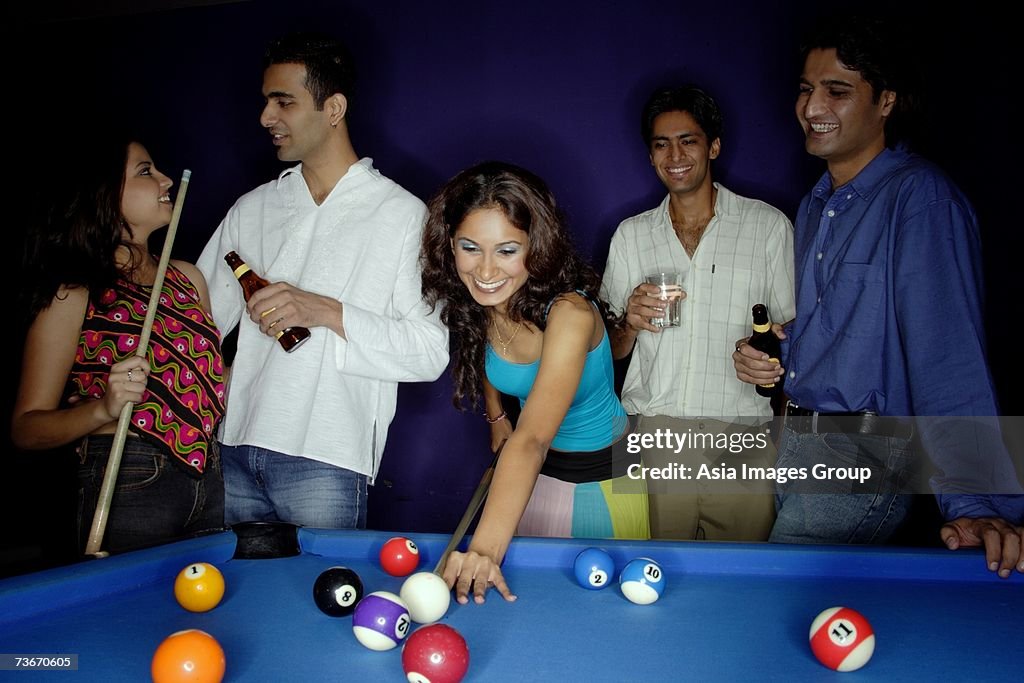 Young adults playing pool and drinking beer
