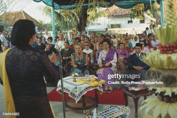 Queen Juliana of the Netherlands pictured seated wearing sunglasses in centre as she listens to a speaker during a Dutch royal visit to Jakarta,...
