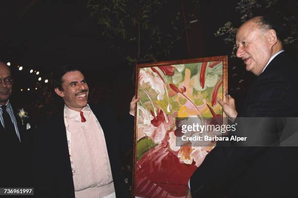 American pop artist Peter Max and Mayor of New York City Ed Koch holding one of Max's paintings, New York City, circa 1983.