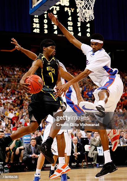 Aaron Brooks of the Oregon Ducks drives around Corey Brewer of the Florida Gators during the midwest regionals of the NCAA Men's Basketball...