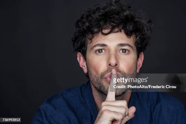 man silencing with finger held to lips - shh stock pictures, royalty-free photos & images