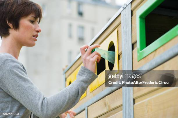 woman placing plastic bottle in recycling bin - recylcebak stockfoto's en -beelden