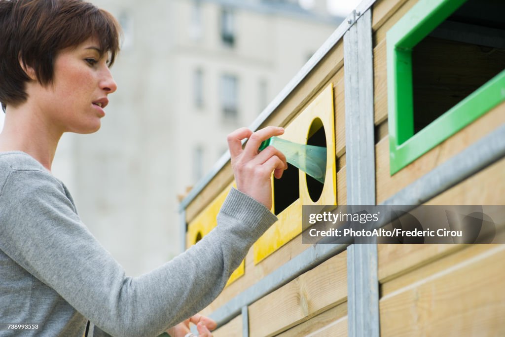 Woman placing plastic bottle in recycling bin