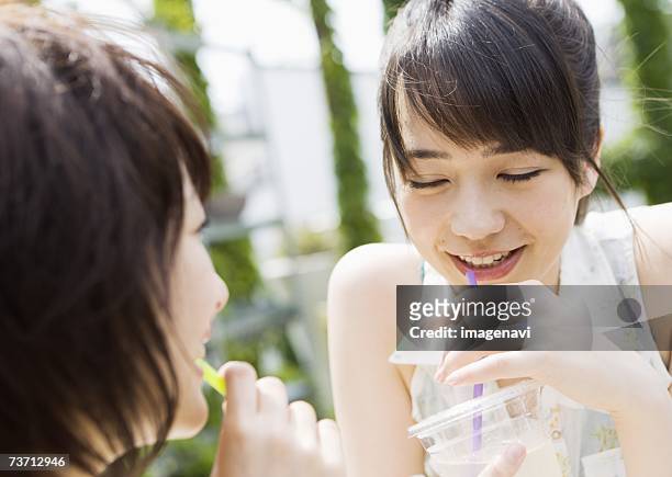 two young girls drinking juice - rietje los stockfoto's en -beelden