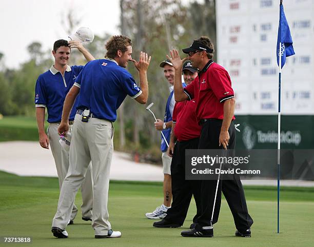 Ian Poulter of England and the Lake Nona team watched by his playing partner Justin Rose of England reacts with his opponent Robert Allenby of...