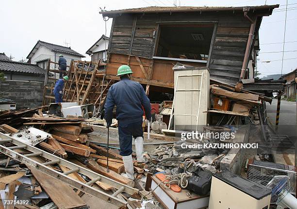 Workers clean up rubble from a badly damaged house in Wajima, Ishikawa prefecture, 27 March 2007, two days after a strong earthquake hit the region....