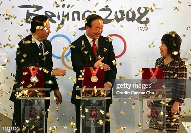 Chinese officials Cai ZhenHua, Jiang XiaoYu and Deng YaPing celebrate after unveiling the winning medals for the Beijing 2008 Olympic Games on March...