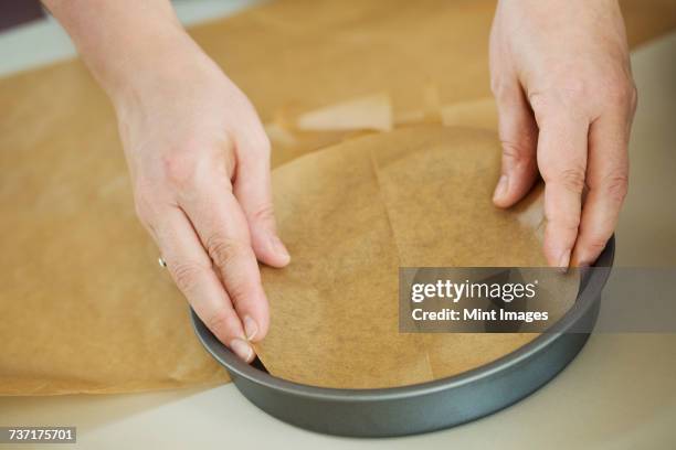 close up high angle view of person lining the bottom of a round baking tin with baking paper. - baking dish stock pictures, royalty-free photos & images