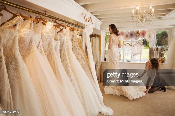 rows of wedding dresses on display in a specialist wedding dress shop. - robe de mariée photos et images de collection