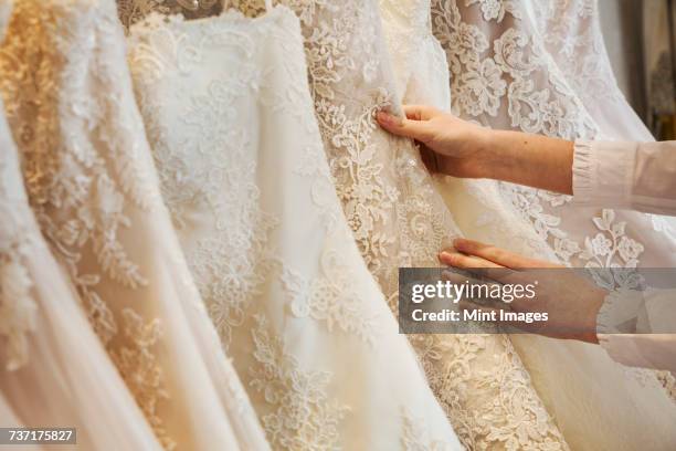 rows of wedding dresses on display in a specialist wedding dress shop. close up of full skirts, some with a lace overlay, in a variety of colour tones. . - brautkleid stock-fotos und bilder