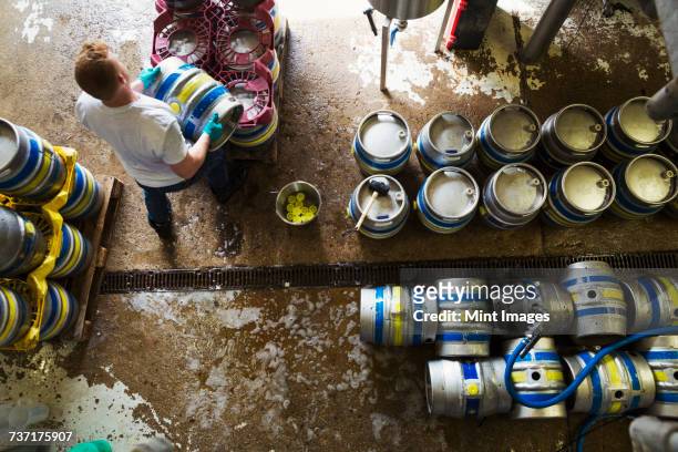 directly above view of a man working in a brewery, metal beer kegs standing on the floor. - berkshire england stock pictures, royalty-free photos & images