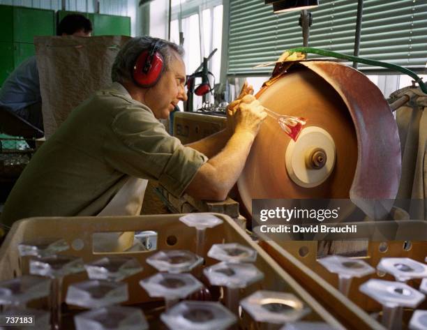 Concentrating on not breaking a crystal wine glass, a buffer at Moser's factory uses a spinning wheel to smooth the roughness from the base of the...
