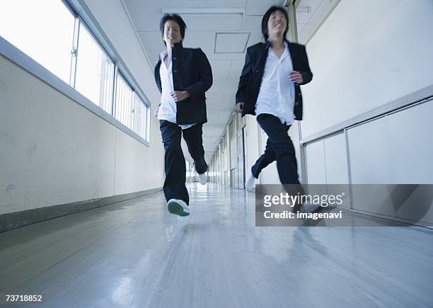 two young schoolboys running in corridor - 学生服 ストックフォトと画像