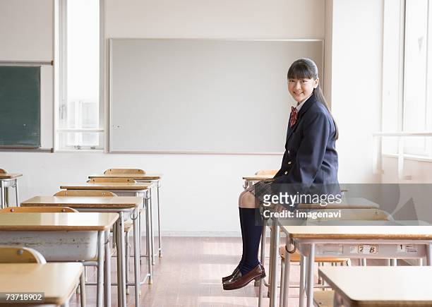 smiling teenagegirl sitting on school desk - japan 12 years girl stock pictures, royalty-free photos & images