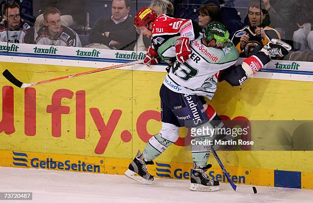 Anton Bader of Nuremberg tackles Andreas Morczinietz of Hanover during the DEL Bundesliga play off quarter final game between Hanover Scorpions and...