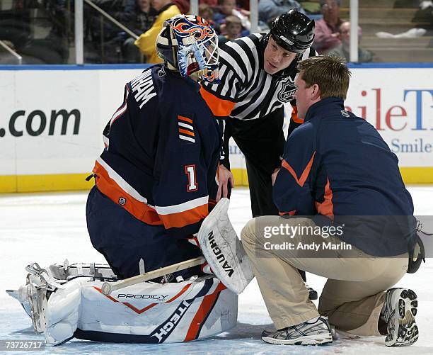 Mike Dunham of the New York Islanders is tended to by trainer Garrett Timms and referee Gord Dwyer ater being injured against the New Jersey Devils...