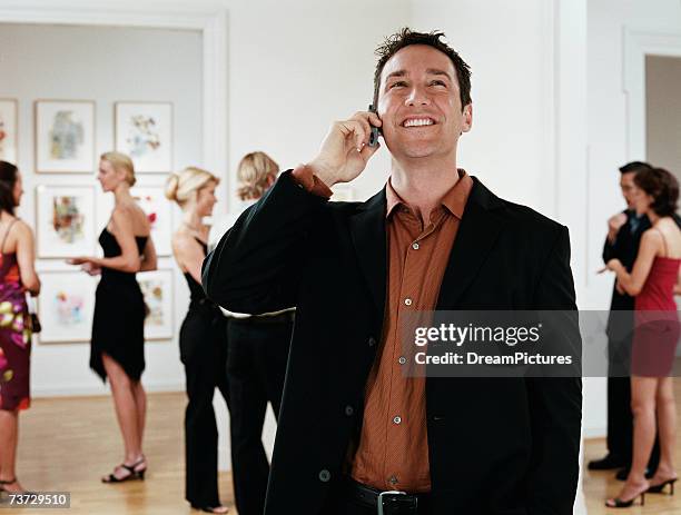 man on cellphone in art gallery - art gallery party stock pictures, royalty-free photos & images