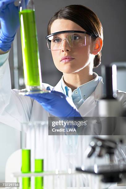 female scientist examining chemical cylinder in lab, close-up - bioquímica - fotografias e filmes do acervo