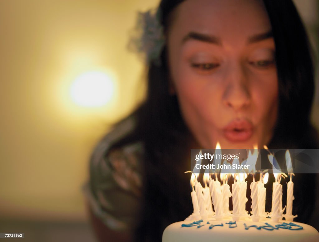 "Woman blowing out candles on birthday cake, focus on candles"