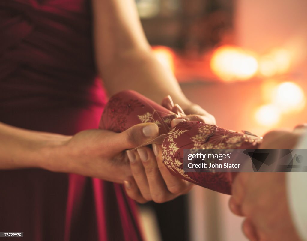 "Woman and man pulling Christmas cracker, mid section"