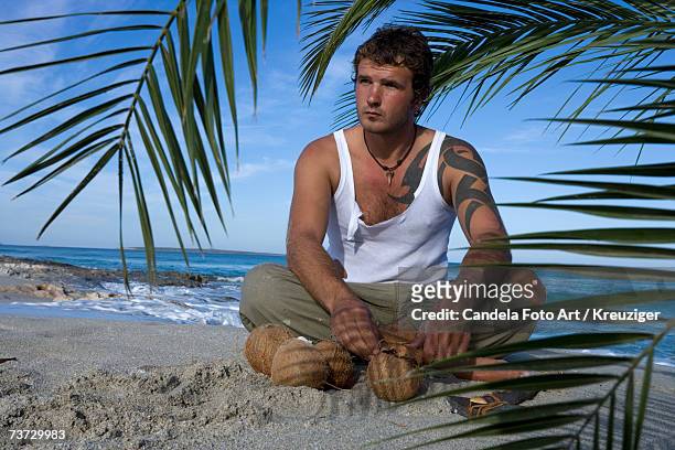man sitting on beach with coconuts - the castaway ストックフォトと画像