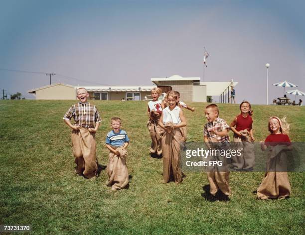 Group of children having a sack-race, circa 1960.