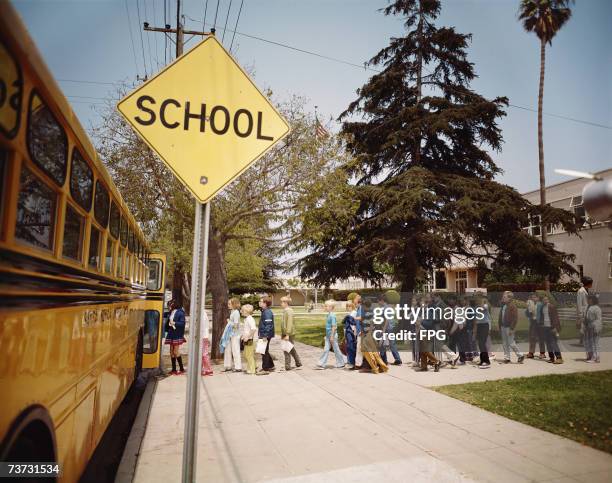 Group of schoolchildren boarding a school bus on their way home, Santa Monica, California, circa 1970.