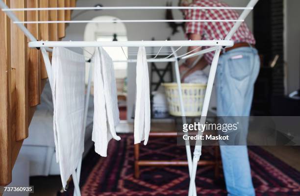 clothes hanging on drying rack while senior man standing in background - drying stock pictures, royalty-free photos & images