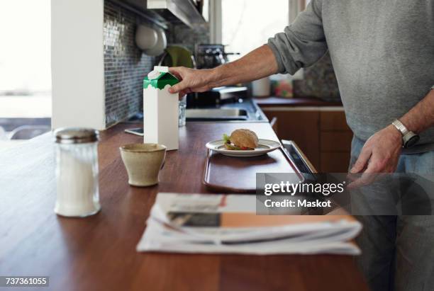 midsection of senior man preparing breakfast at kitchen counter - cartón de bebida fotografías e imágenes de stock