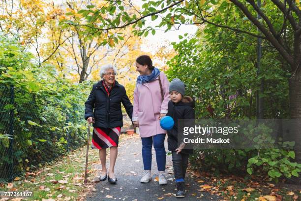 full length of happy senior woman walking with daughter and great grandson in park - grandma cane stock pictures, royalty-free photos & images
