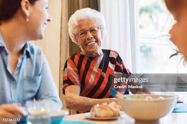 happy senior woman talking to daughter at dining table - great grandmother fotografías e imágenes de stock