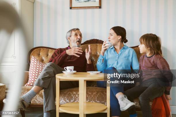 senior man talking to daughter and great grandson on sofa in living room - senior men coffee stock pictures, royalty-free photos & images