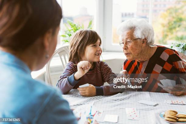 happy boy showing playing card with great grandmother at home - poker card game stock pictures, royalty-free photos & images