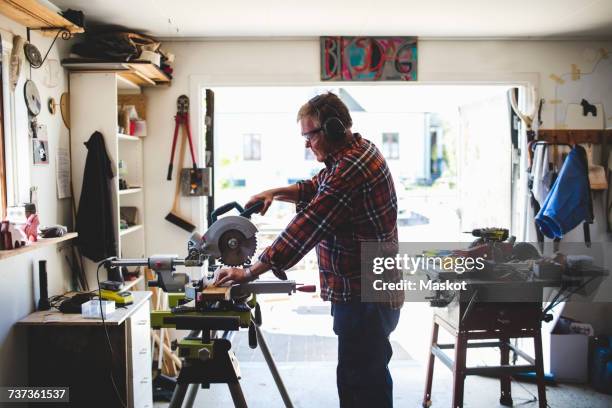 side view of senior man using circular saw in workshop - circular saw stockfoto's en -beelden