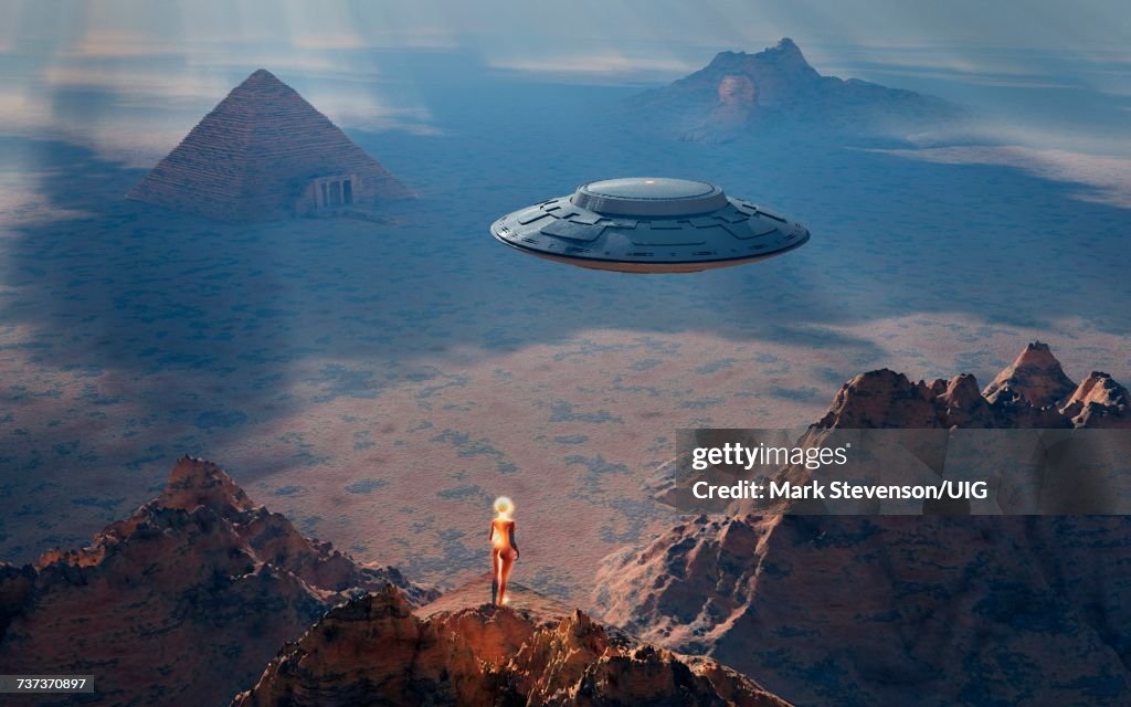 Robot Standing On Rock Outcrop Looking Down On Ancient Pyramid.