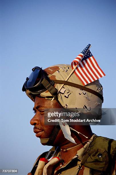 Marine arrives at Dhahran air base from the USA with his Stars and Stripes flag flying proudly from his helmet, during the Gulf War, December 1990.